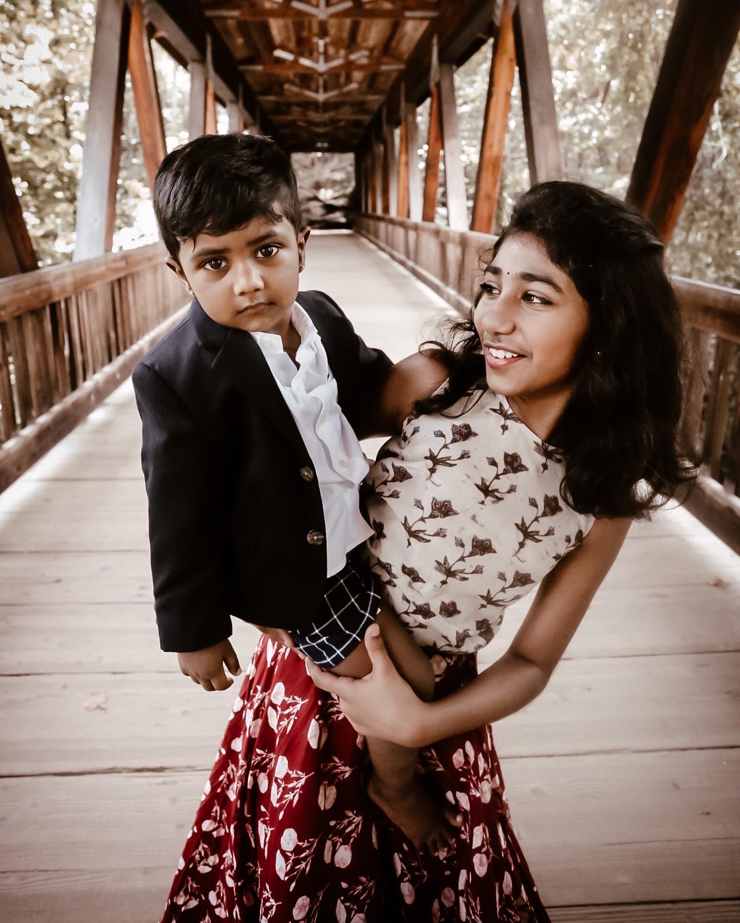 Big sister holding her little brother while looking at him and smiling