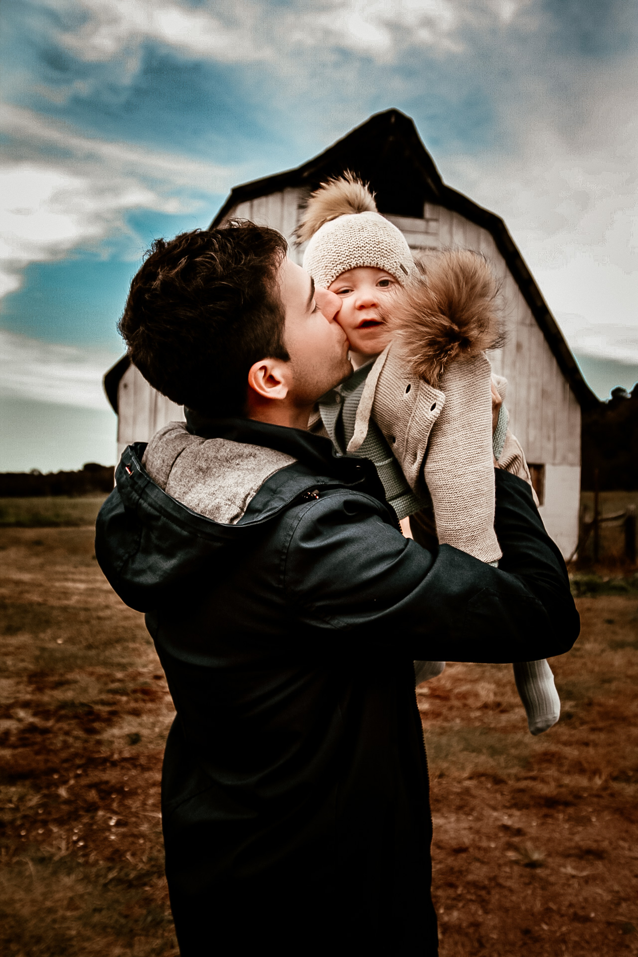 Father holding his son u in air and kissing him on the check with a ban in the background - Location - Vaughter' Barn in Atlanta, Ga