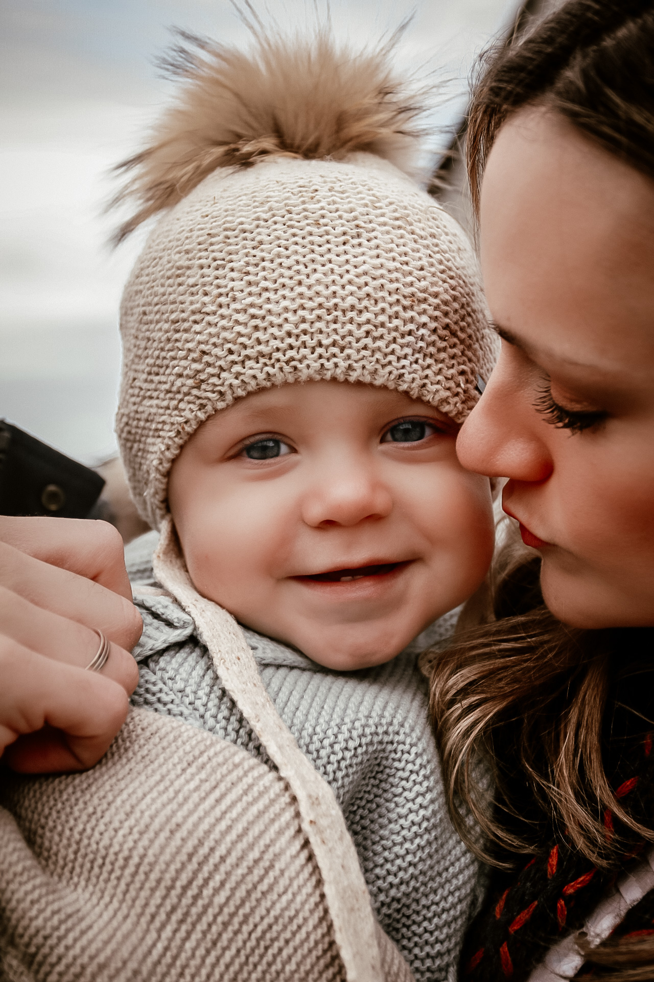 Mom holding her young son while looking at him and son is smiling at the camera