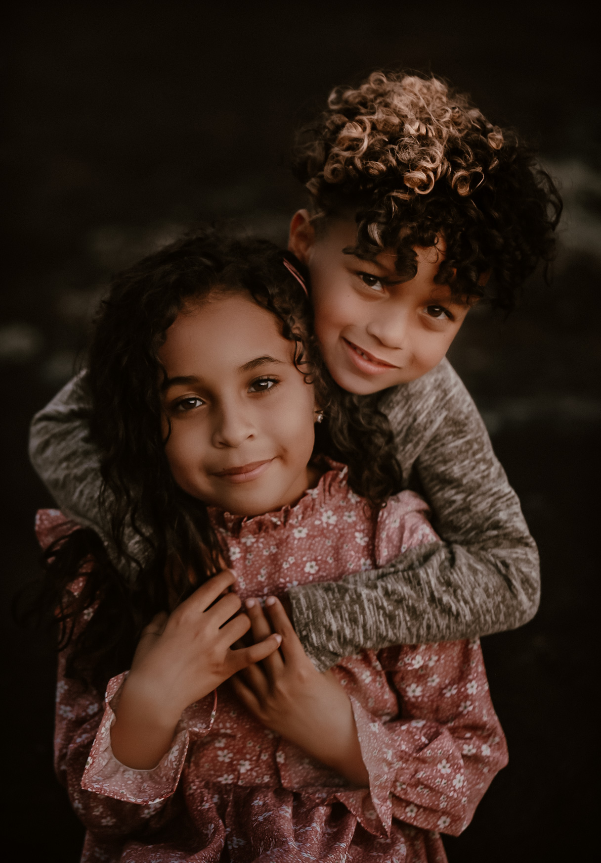 Brother hugging his big sister from behind and both smiling at the camera- Location - Arabia Mountain Atlanta, GA