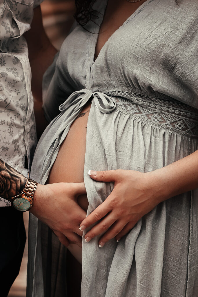 Close up of pregnant moms belly while both husband and wife are holding belly