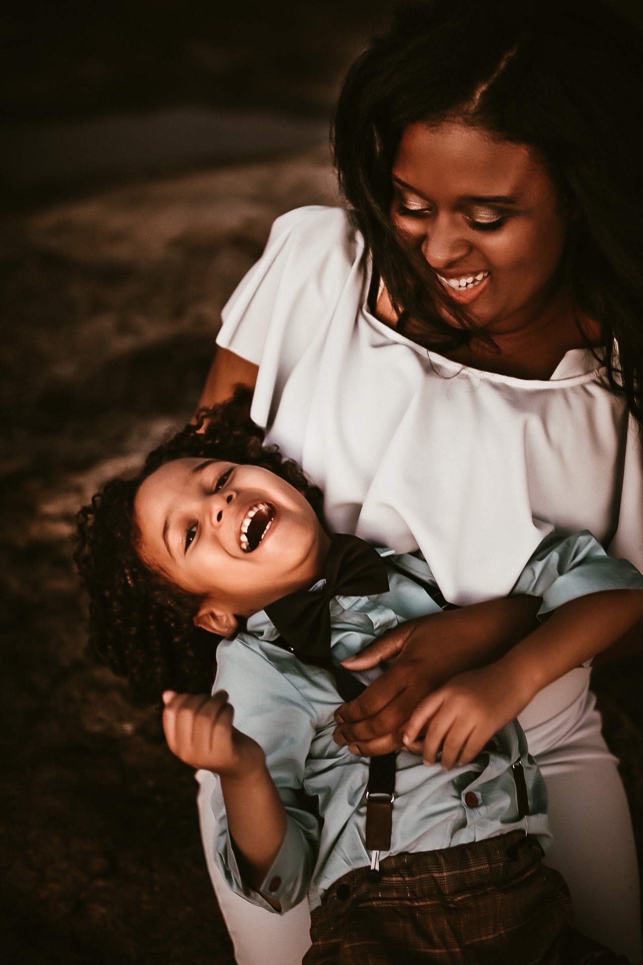 Little boy in moms lap while laughing aand mom looking down at him smiling and laughing. Fall Family photography - - Arabia Mountain Family Portrait Photography