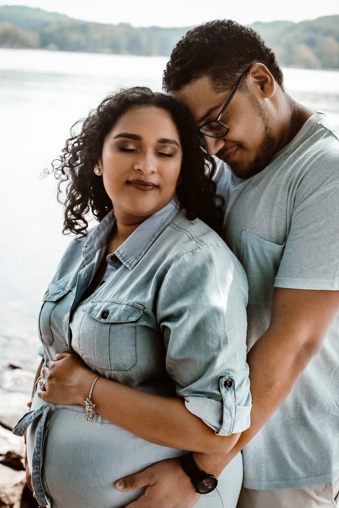 Husband and wife portrait of husband standing behind wife while bother holding her belly