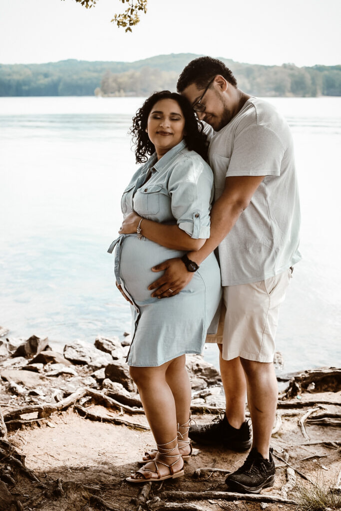 Husband and wife portrait of husband standing behind wife while bother holding her belly