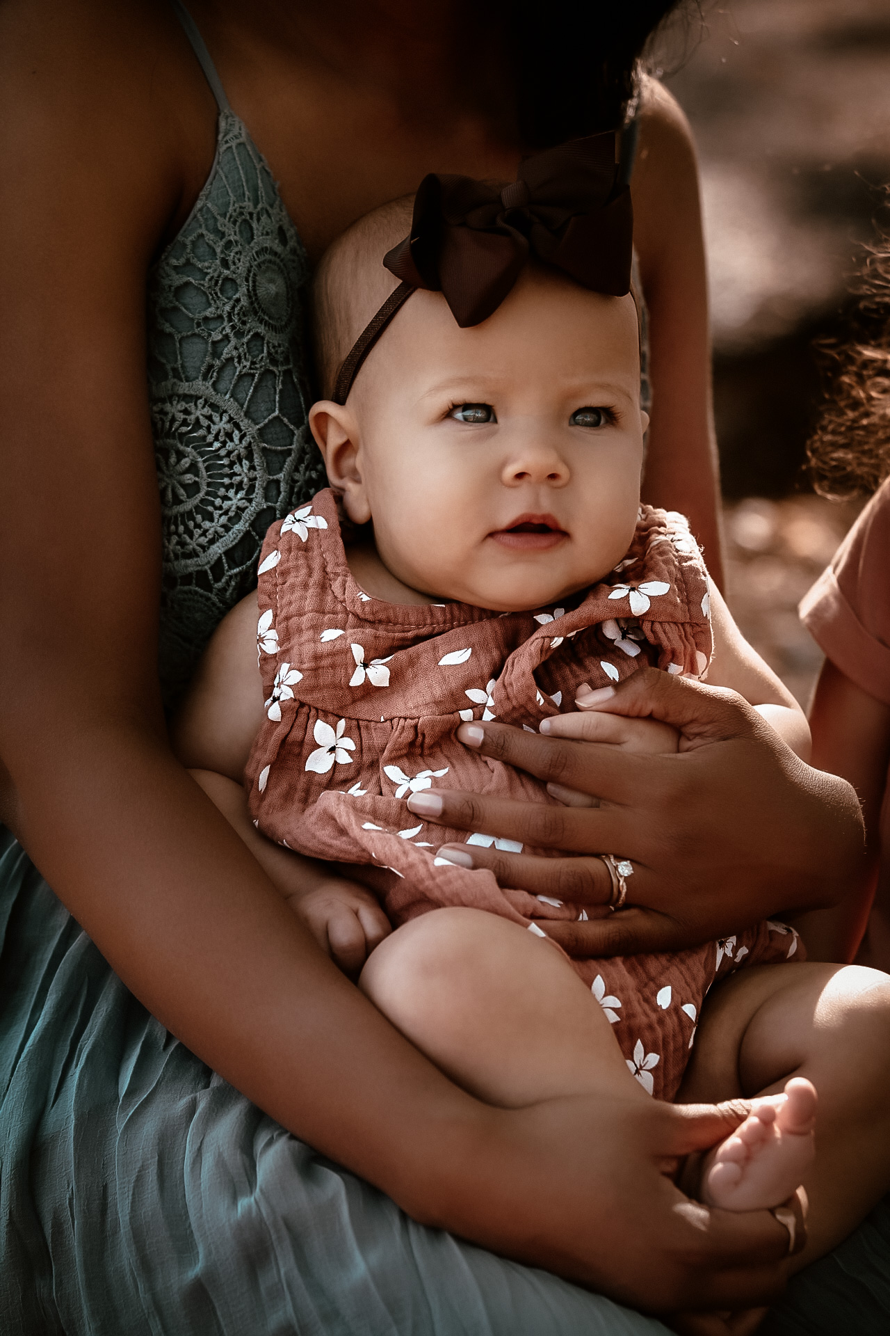 Little baby sitting on her moms lap while looking in the distance - Red Top Mountain Family Photography