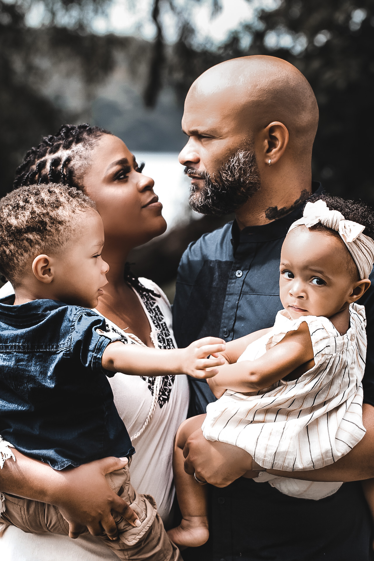 Husband and wife looking at each other while both holding their daughter and son