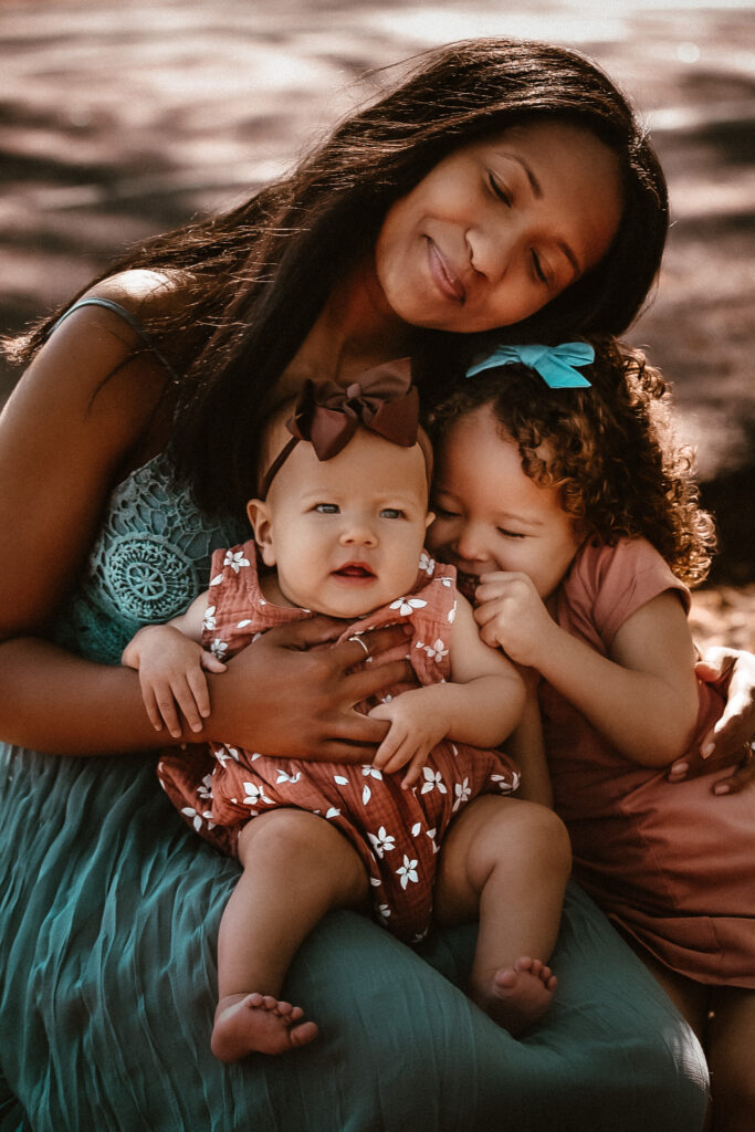 Mom with her two young girls all hugging each other and smiling with their eyes closed-. Red Top Mountain Family photography- Link to the full gallery of this session