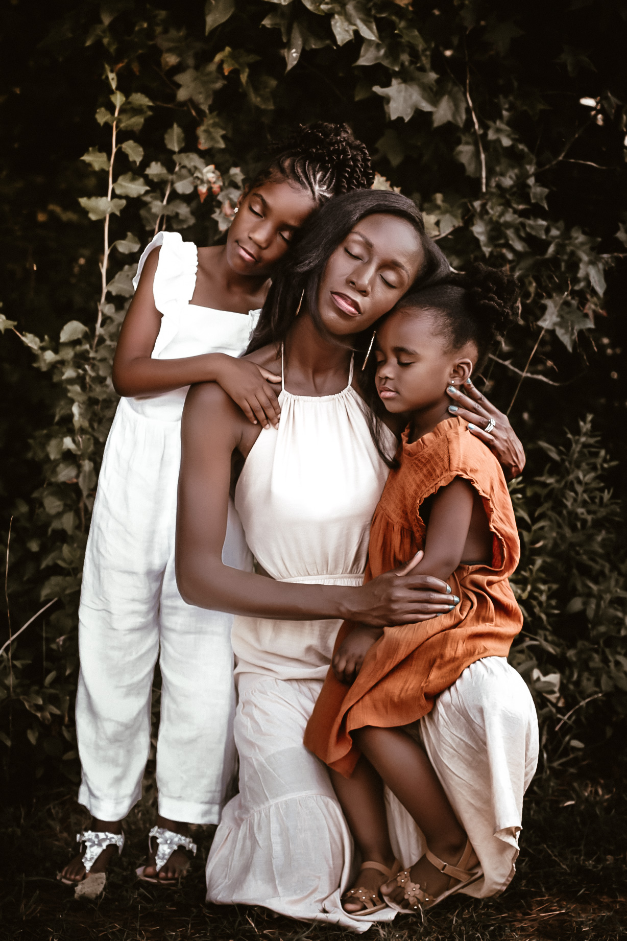 Mom with her two daughters all hugging and having their eyes closed