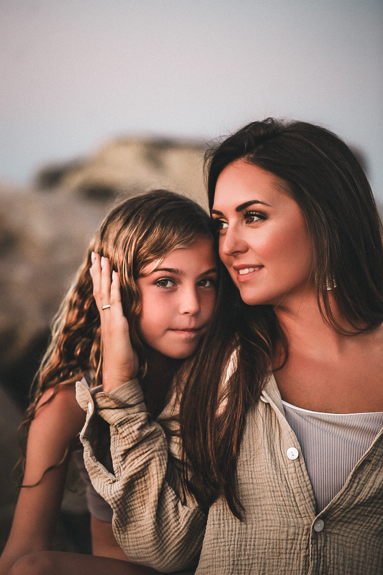 Mom and daughter hugging each other while mom and looking off into the distance and daughter is looking at the camera awith a soft smile. Fall Family photography - - Destin Florida Portrait Photography