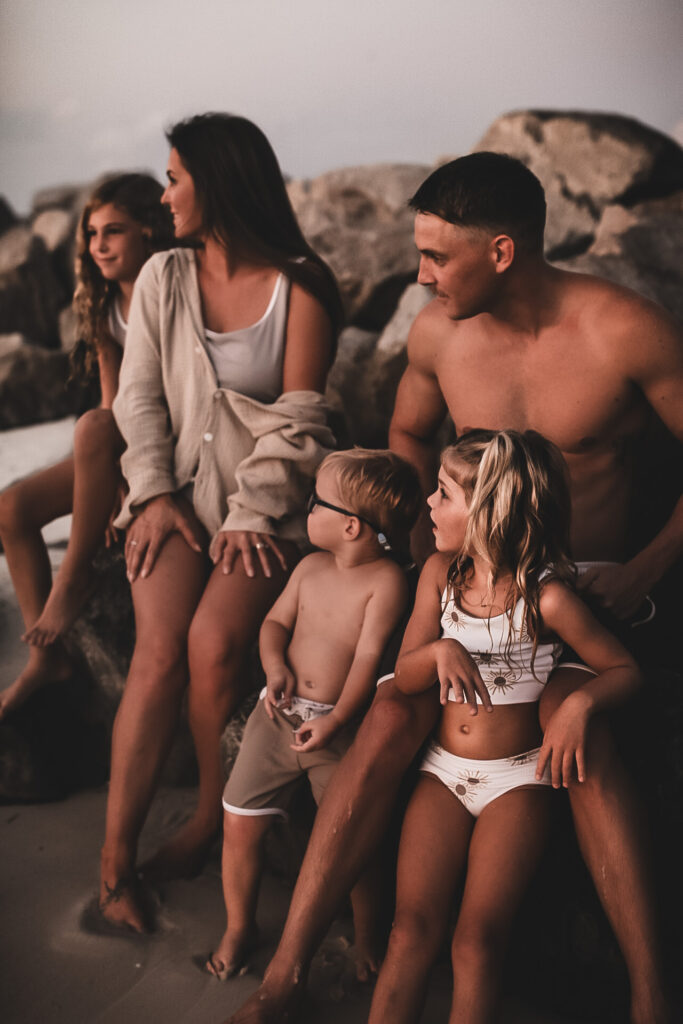 Family of 5 at St. Andrews's State Park in Florida- sitting on the rocks and smiling at each other 0Fall Family photography - - Destin Florida Portrait Photography- Link to the full gallery of this session