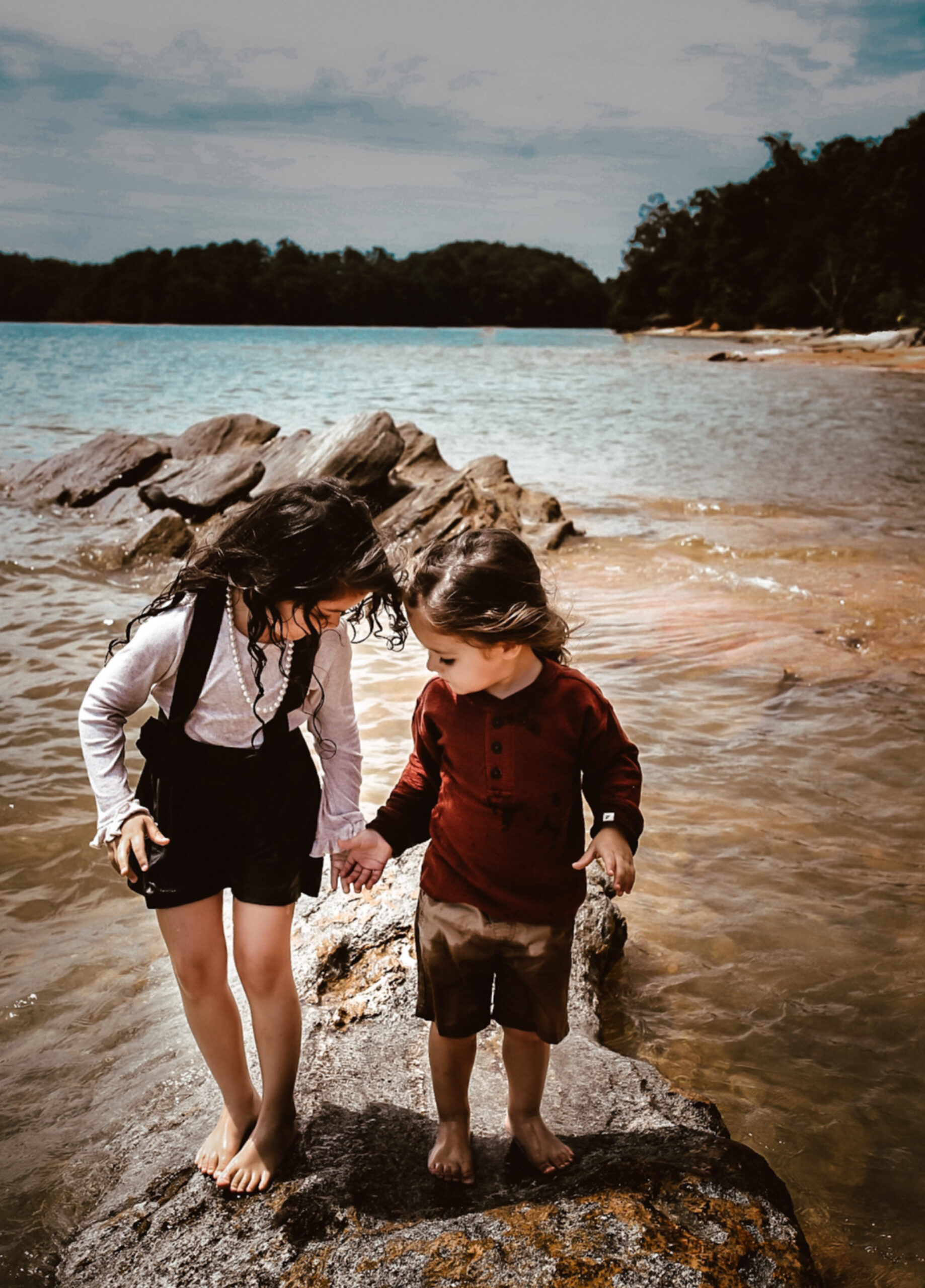 Brother and sister holding hands while standing in the water at Lake Lanier