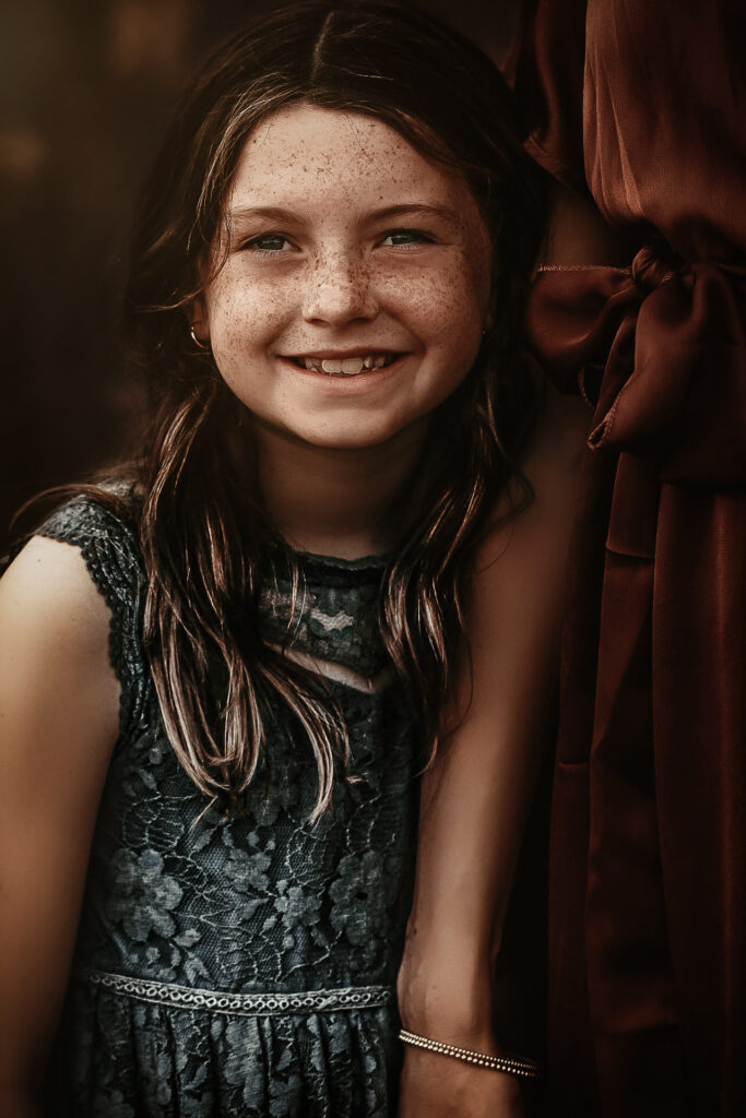 Close up of young Daughter holding her moms arm and smiling at the camera