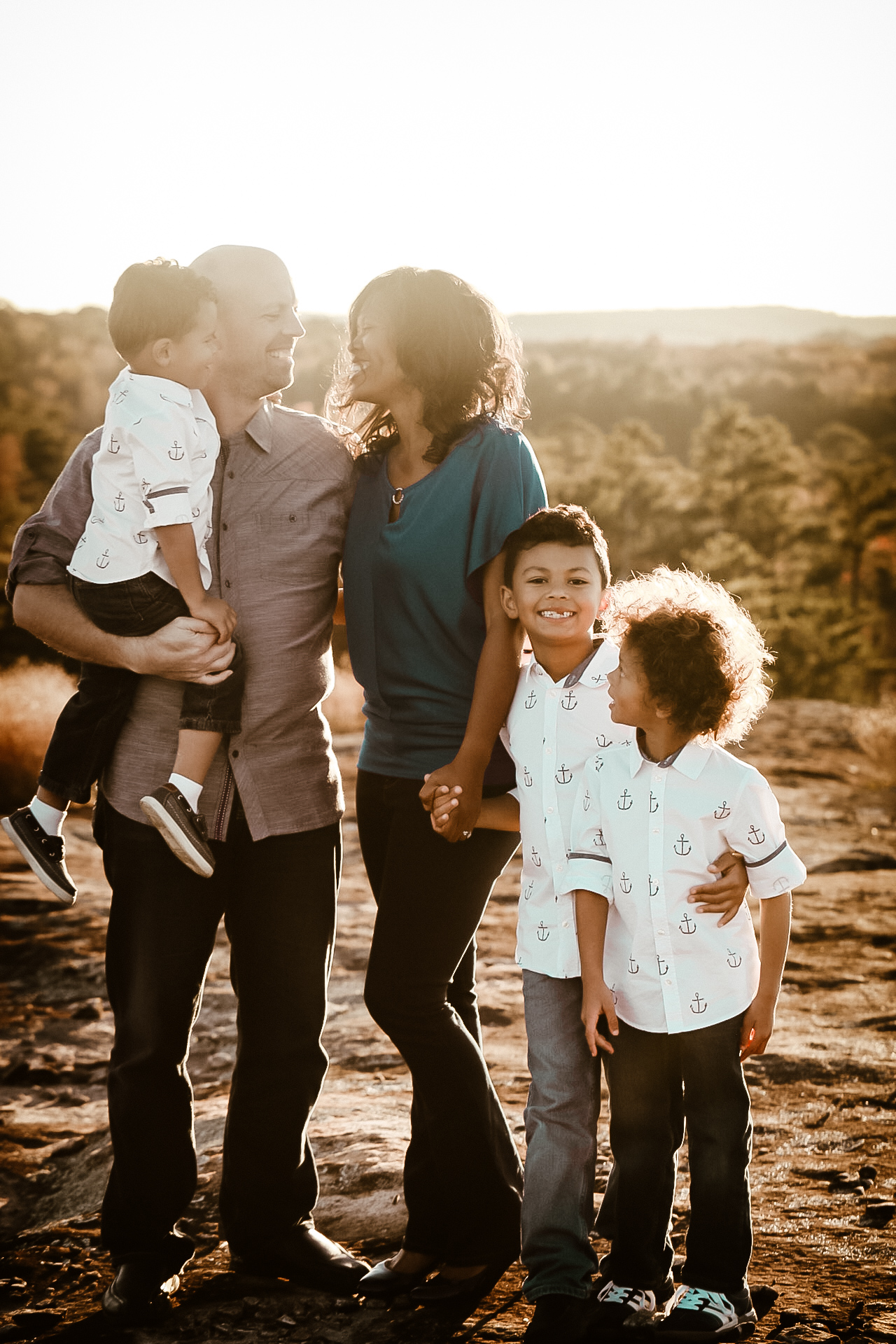 Family of 5 on top of a mountain during sunset looking at each othehr and smiling. Family Portrait Atlanta Georgia - Arabia Mountain