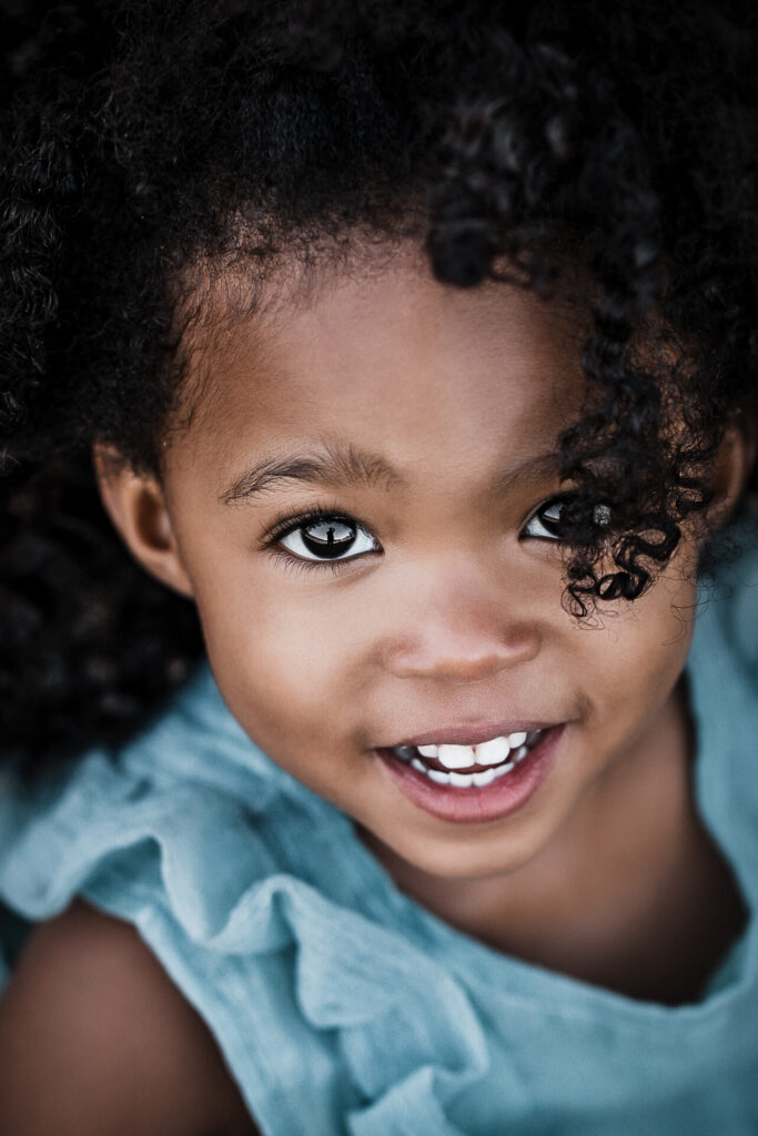 Little girl in blue dress smiling for the camera - teeth showing for children's dentistry