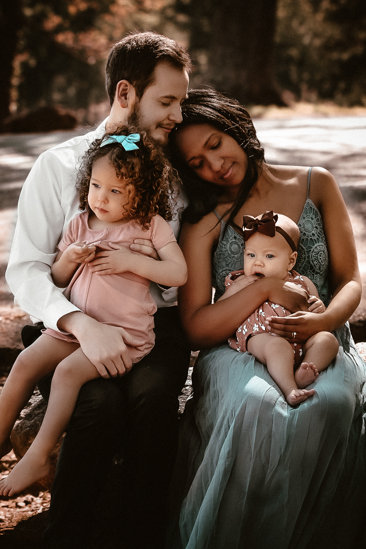 Family of 4 mom and dad holding baby while mom lays on her husbands shoulder and daughters looking in the distance - Red Top Mountain Atlanta, Ga