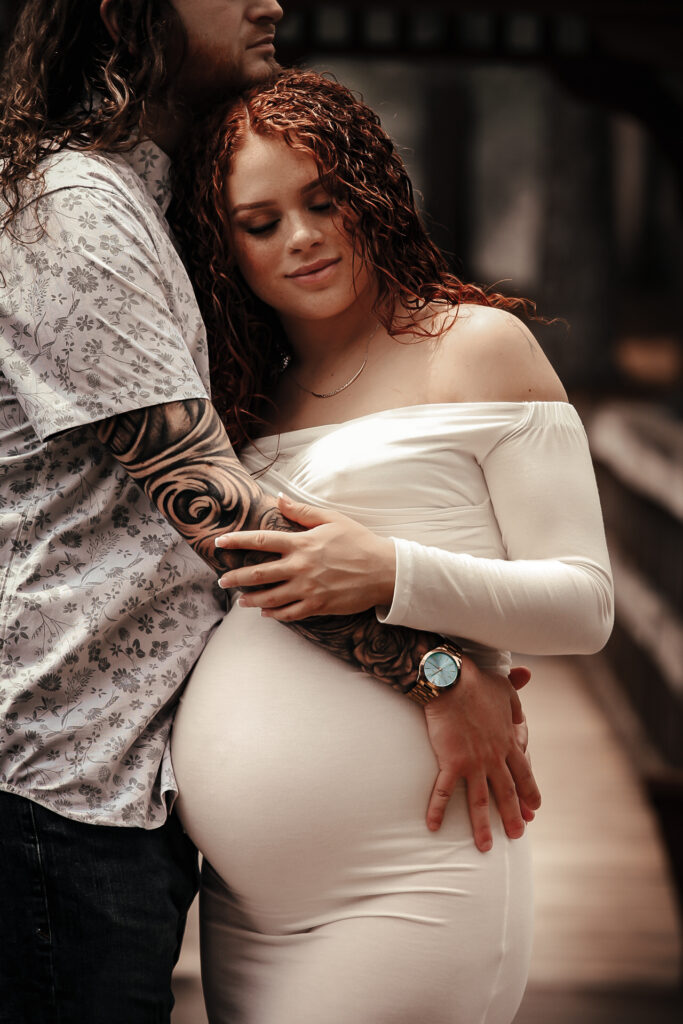 Husband holding his pregnant wife while looking down eyes closed