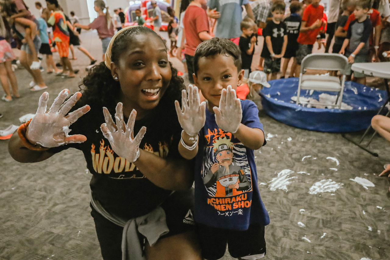 A photo of Ashley, owner of Ashley Aria Photography, with a child from summer camp called Woodlands Camp. Having fun with shaving cream, to show personality and connection to children