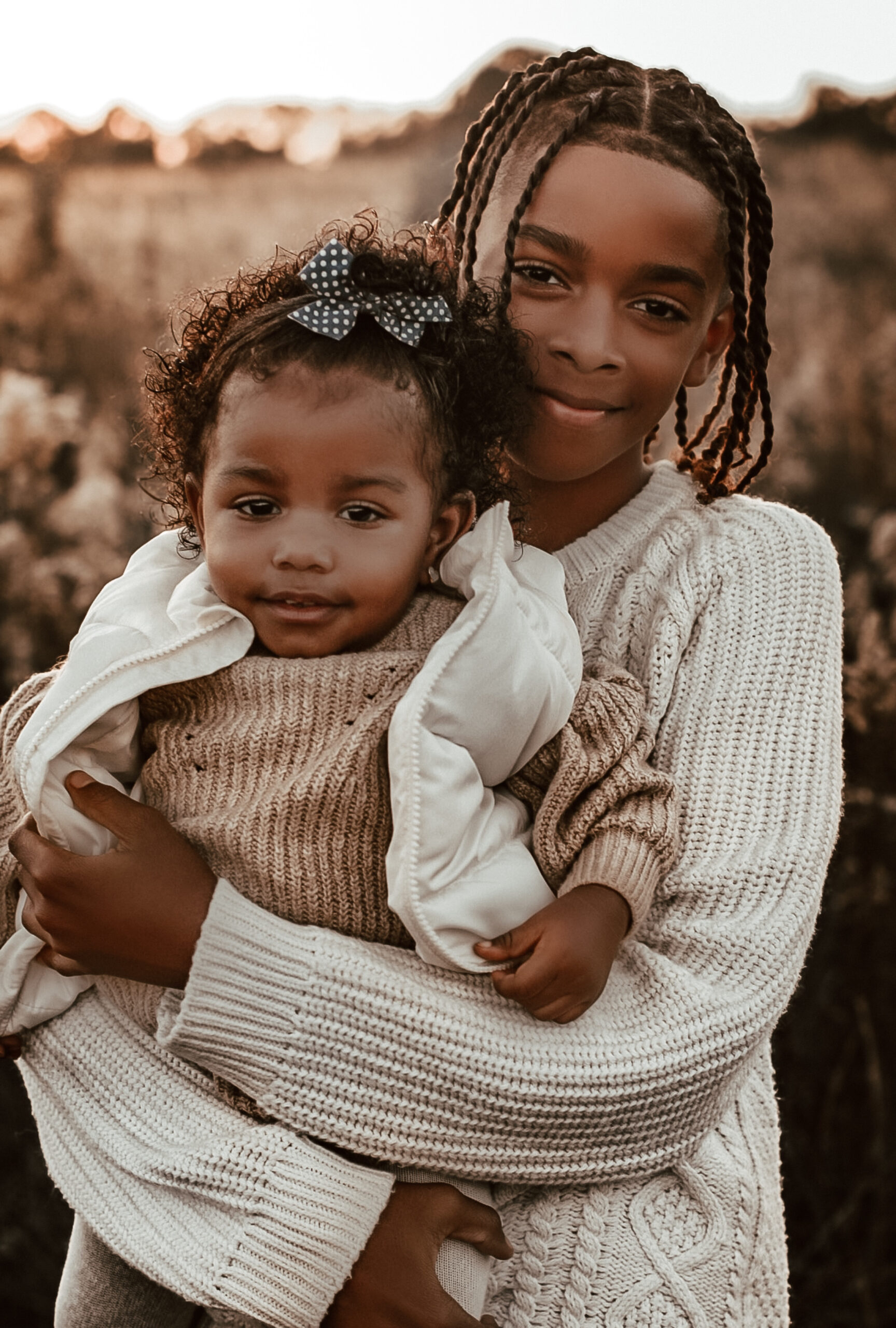 Brother holding his baby sister while smiling at the camera