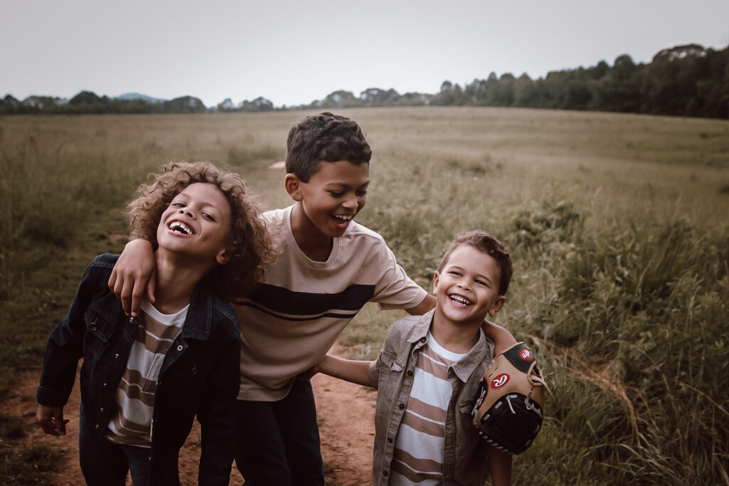 Three brothers in a big open field in Atlanta, GA laughing with each other