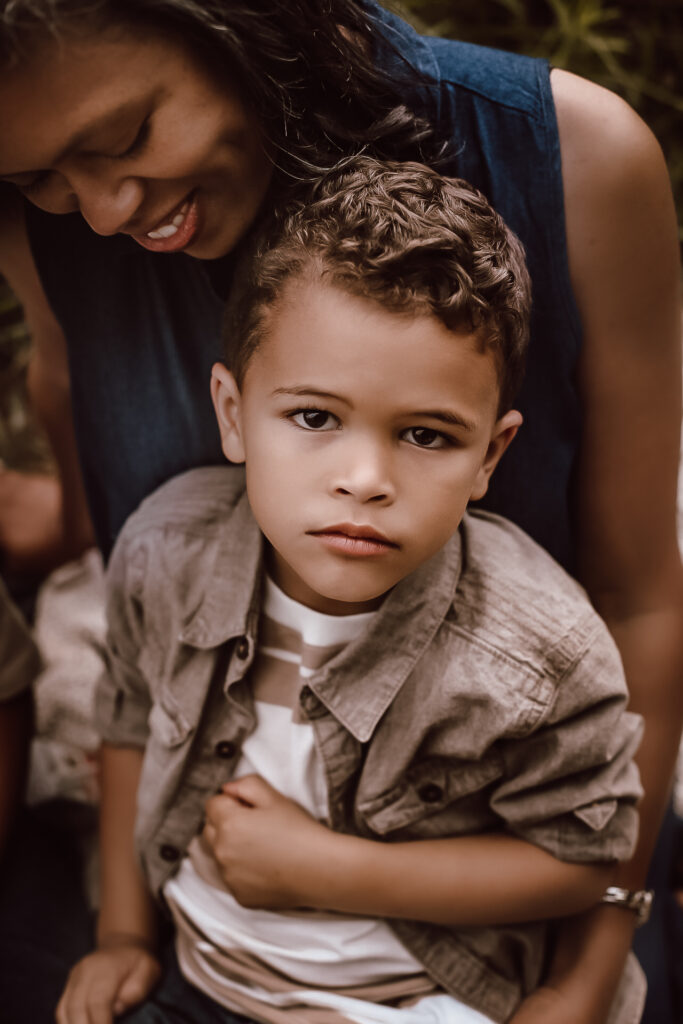 Little boy in moms lap looking at the camera in a big field in Atlanta Ga