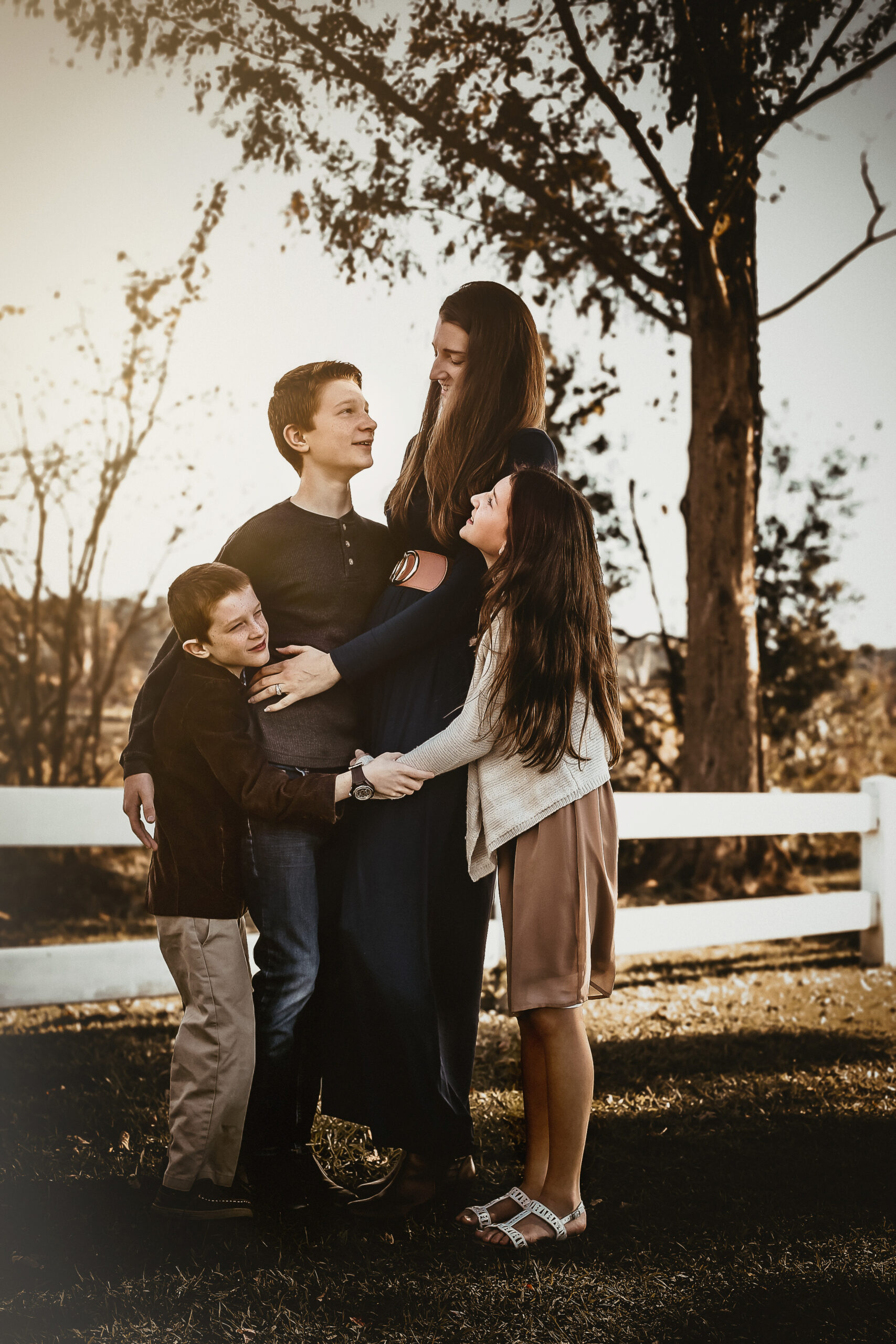 Family of 4 hugging each other at the beach and smiling at eachother