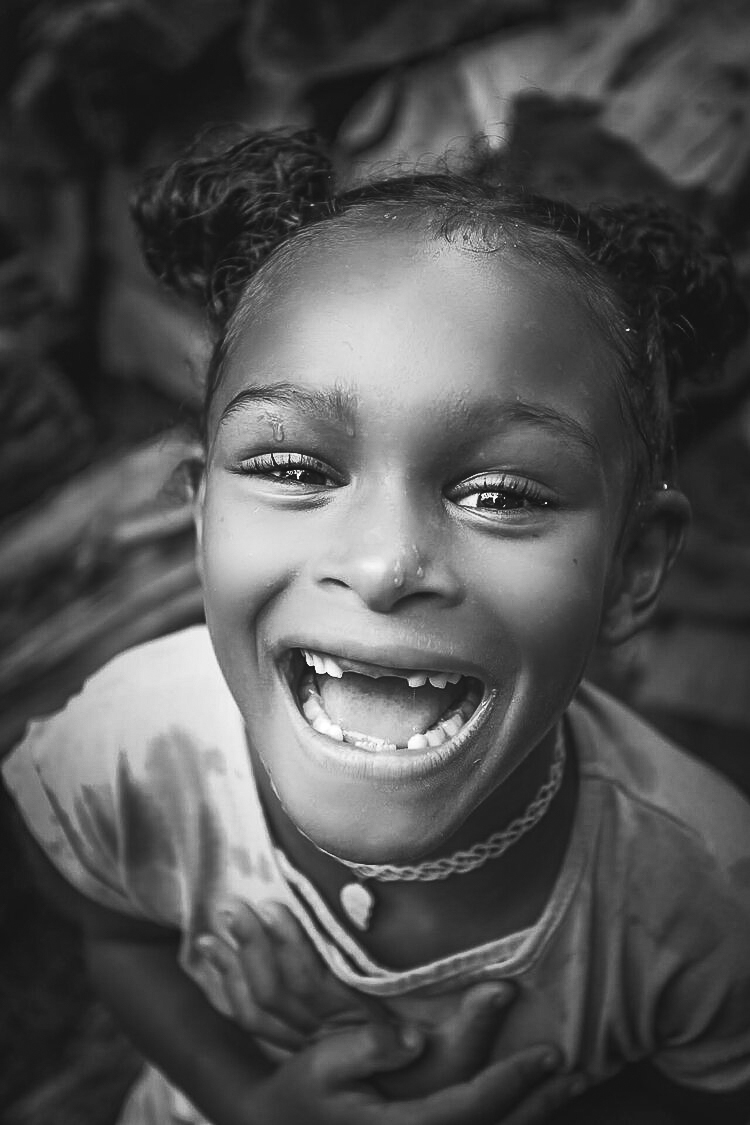 Black and white portrait of a young girl laughing and smiling at the camera