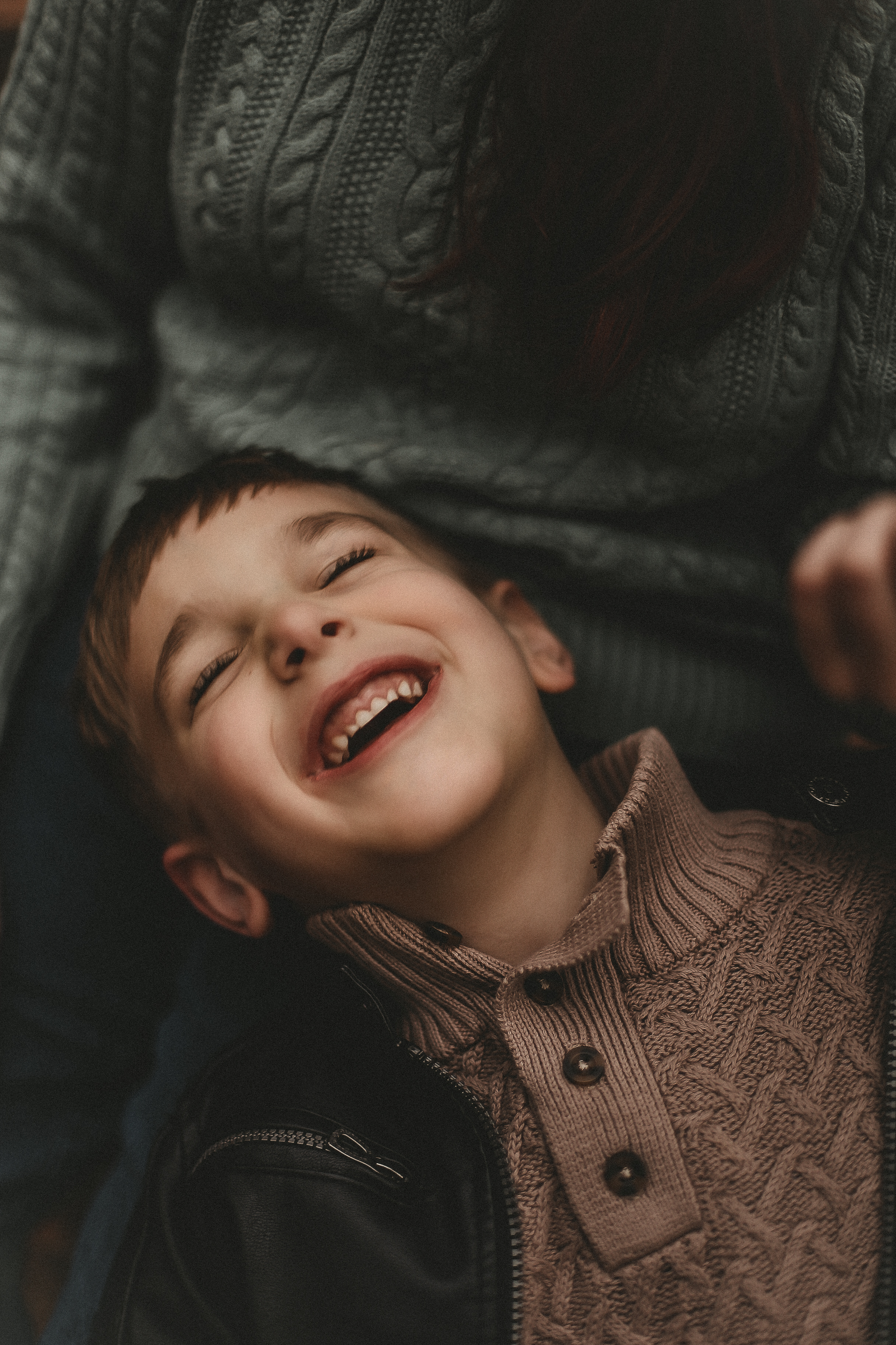 Young boy laying on his sister while laughing