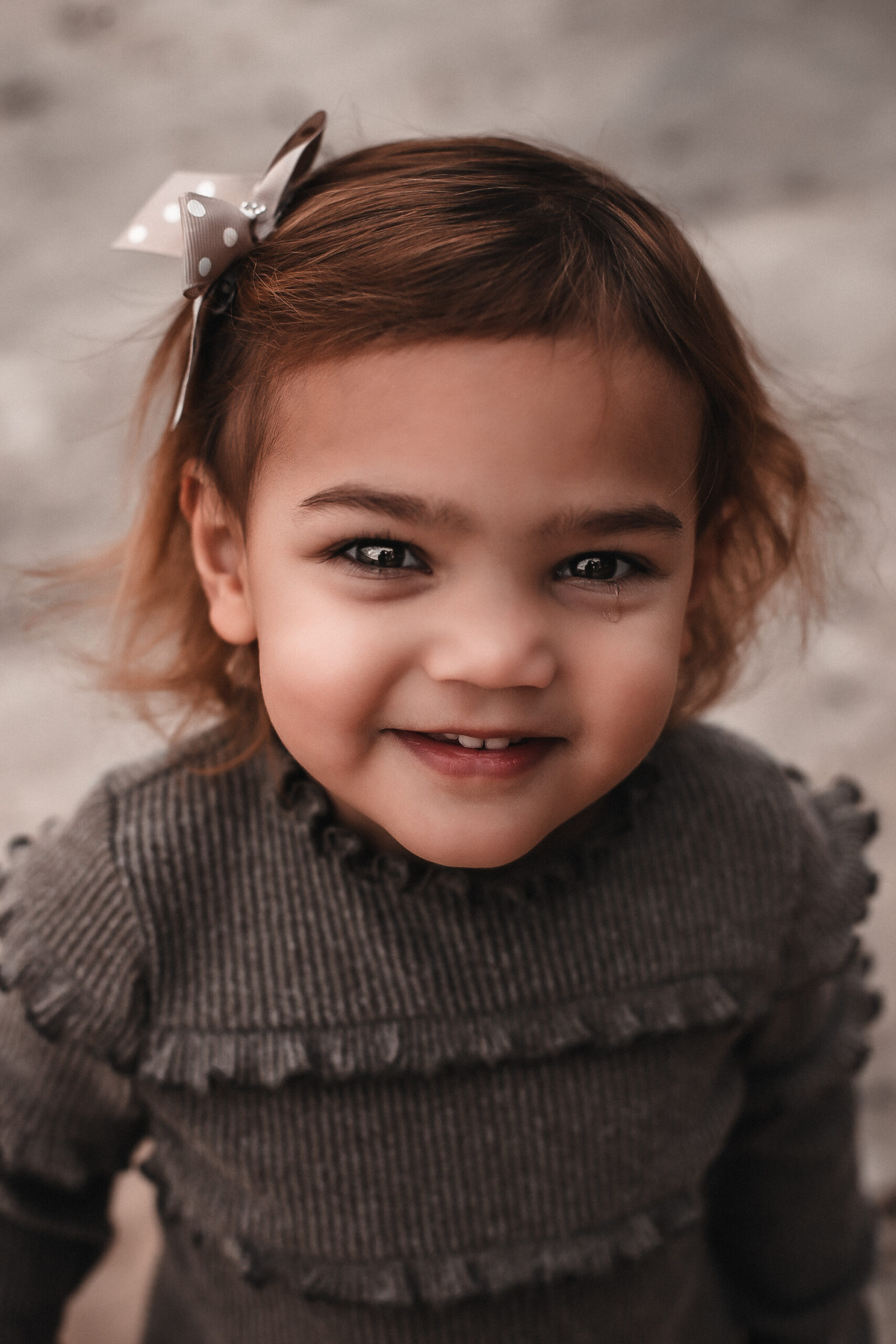 Close-up portrait of a little girl at the beach smiling at the camera